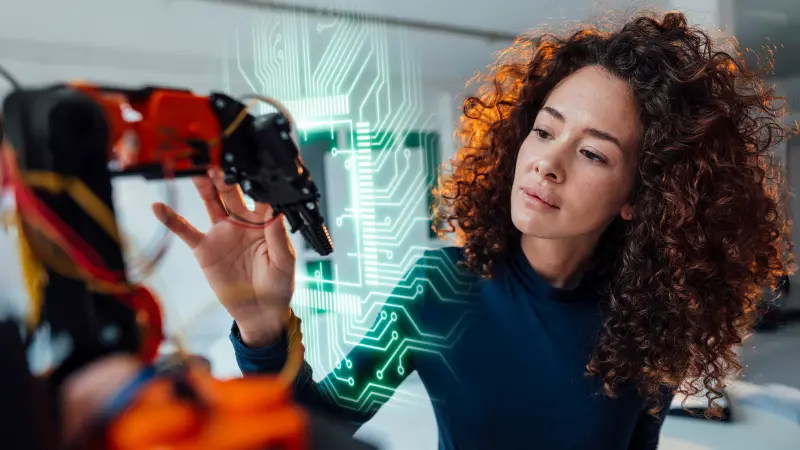 Image of woman marveling at a robotic machine, carefully touching it with its hand. A graphic depiction of PCB circuits with a green glow to symbolize the copperdot PCB service.