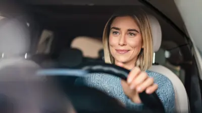 Bild einer Frau am Steuer eines Autos, die selbstbewusst nach vorne blickt