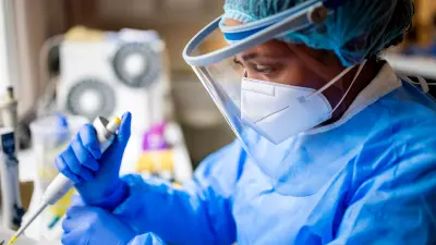 Foto einer MTA in Schutzkleidung, die in einem medizinischem Labor arbeitet