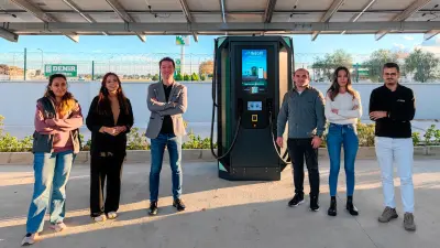 Imecar team standing beside an electric vehicle charging station, illustrating their success with PCB solutions from copperdot.